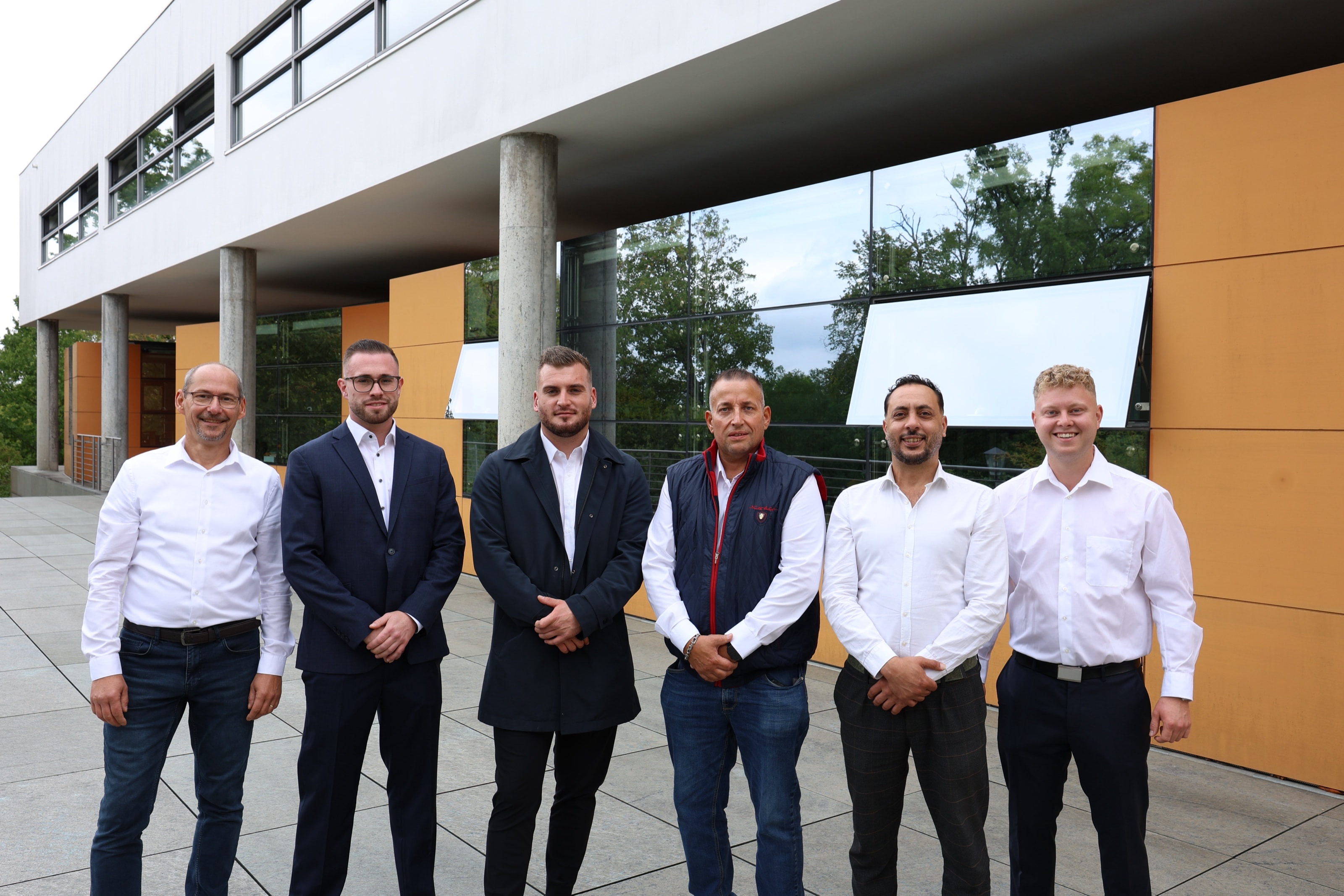 Das Team von Reinhold & Partner vor dem modernen Bürogebäude